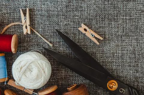 Retro sewing tools: old scissors, bobbins of thread on gray fabric. Tailor's  Stock Photos