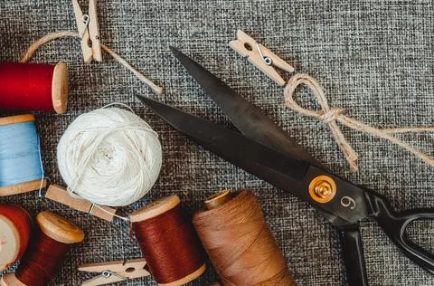 Retro sewing tools: old scissors, bobbins of thread on gray fabric. Tailor's  Stock Photos