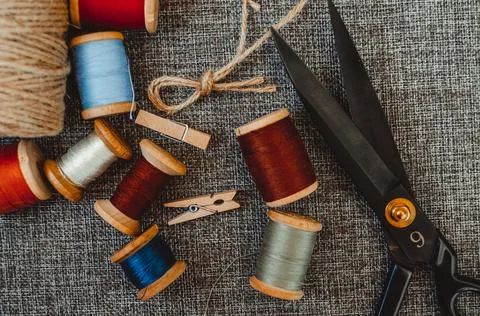 Retro sewing tools: old scissors, bobbins of thread on gray fabric. Tailor's  Stock Photos