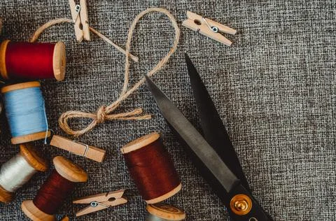 Retro sewing tools: old scissors, bobbins of thread on gray fabric. Tailor's  Stock Photos