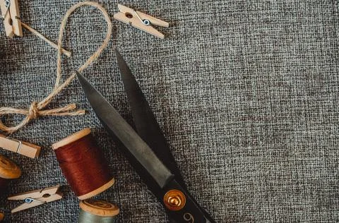 Retro sewing tools: old scissors, bobbins of thread on gray fabric. Tailor's  Stock Photos