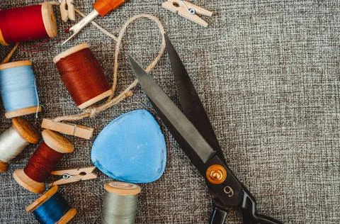 Retro sewing tools: old scissors, bobbins of thread on gray fabric. Tailor's  Stock Photos