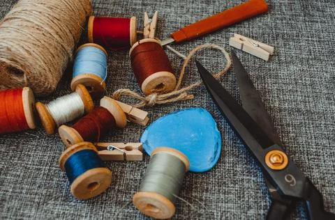 Retro sewing tools: old scissors, bobbins of thread on gray fabric. Tailor's  Stock Photos