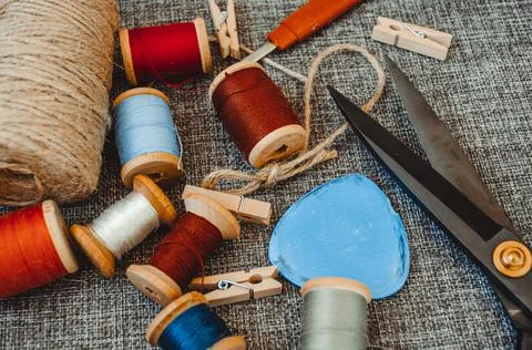 Retro sewing tools: old scissors, bobbins of thread on gray fabric. Tailor's  Stock Photos