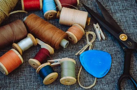 Retro sewing tools: old scissors, bobbins of thread on gray fabric. Tailor's  Stock Photos