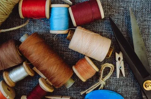 Retro sewing tools: old scissors, bobbins of thread on gray fabric. Tailor's  Stock Photos