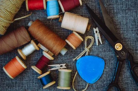 Retro sewing tools: old scissors, bobbins of thread on gray fabric. Tailor's  Stock Photos