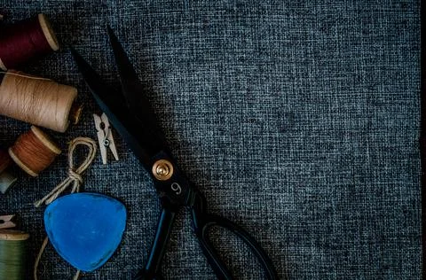 Retro sewing tools: old scissors, bobbins of thread on gray fabric. Tailor's  Stock Photos