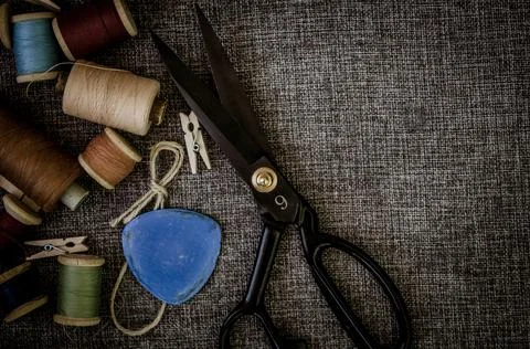 Retro sewing tools: old scissors, bobbins of thread on gray fabric. Tailor's  Stock Photos