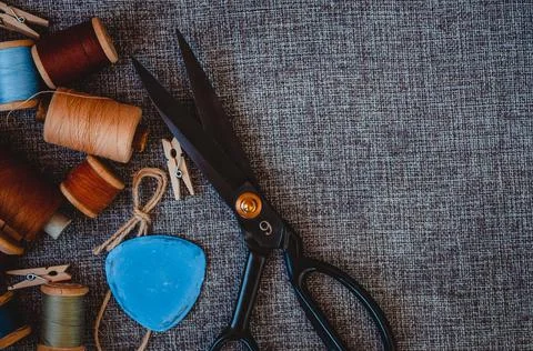 Retro sewing tools: old scissors, bobbins of thread on gray fabric. Tailor's  Stock Photos