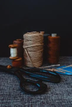 Retro sewing tools: old scissors, bobbins of thread on gray fabric. Tailor's  Stock Photos
