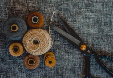 Retro sewing tools: old scissors, bobbins of thread on gray fabric. Tailor's  Stock Photos