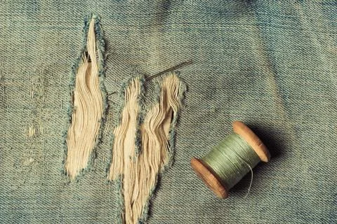 Retro skein thread with a needle on torn, rubbed jeans, sewing jeans, top vie 写真素材