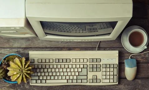 Retro stationary computer on a rustic wooden desk, vintage workspace. Monitor Stock Photos