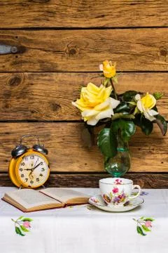 Retro style composition with tea, book, and flowers against wooden background Stock Photos