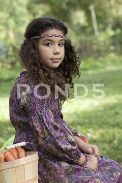 Retro styled girl beside basket of picked carrots Stock Photos