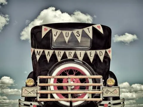 Retro styled image of an old car with just married decoration Stock Photos