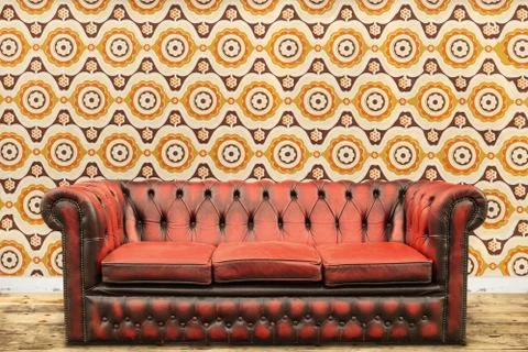 Retro styled image of an old sofa against a vintage wallpaper wall Stock Photos