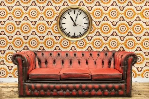 Retro styled image of an old sofa and clock against a vintage wallpaper wall Stock Photos