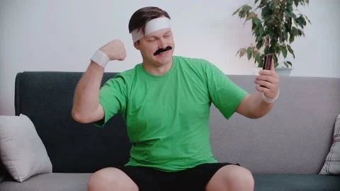 Retro stylish man sitting on the couch and taking a selfie after training. Stock Footage 146265001