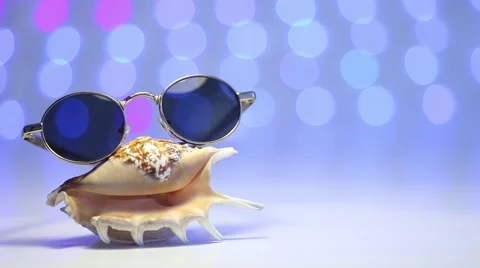 Retro sunglasses with shell and blurry shining colored background Video stock 46015343