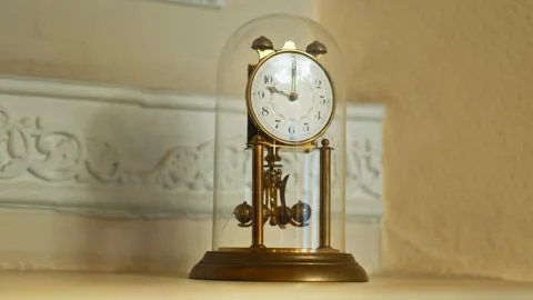 A retro table clock featuring a metal structural design encased within a gl.. Stock Footage 347736513