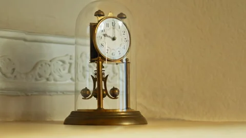 A retro table clock featuring a metal structural design encased within a gl.. Stock Footage 347736584
