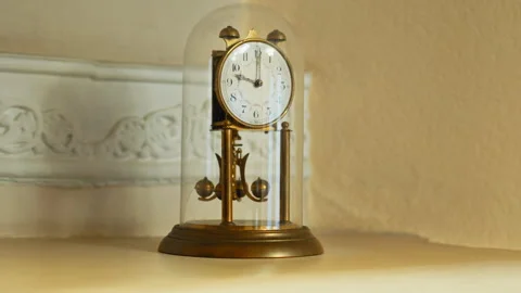A retro table clock featuring a metal structural design encased within a gl.. Stock Footage 347759805