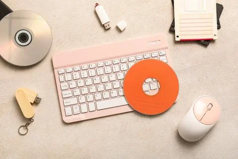 Retro technology flat lay with pink keyboard, floppy disks, cds, and USB driv Stock Photos