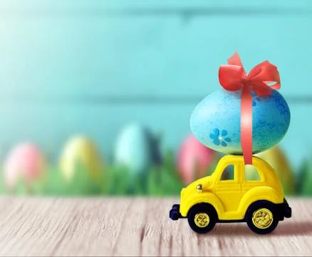 Retro toy car with Easter egg on the roof on spring background. Easter concep Foto stock