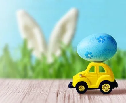 Retro toy car with Easter egg on the roof on spring background. Easter concep Stock Photos