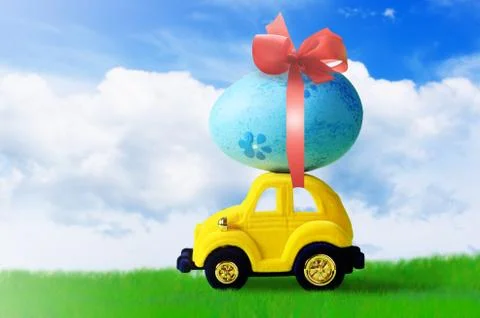 Retro toy car with Easter egg on the roof on spring background. Easter concep Stock Photos
