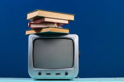 Retro tv receiver with stack of books on classic blue background Stockfoto's