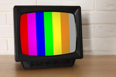 Retro TV set with test pattern on wooden table near white brick wall. Color.. Stockfoto's
