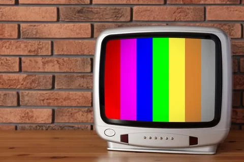 Retro TV set with test pattern on wooden table near brick wall. Color bars .. 스톡 사진