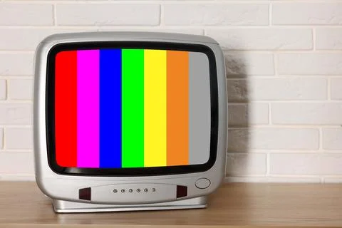 Retro TV set with test pattern on wooden table near white brick wall. Color.. 写真素材