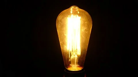 Retro vintage Edison light bulb flickers and turns on against black background. Stock Footage 146579061