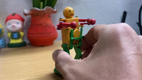 Retro wind up toy robot smiling face dancing by clockwork motor on wooden table Video stock 247954059