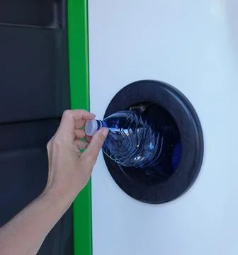 Returning bottles to a plastic recycling machine. 스톡 사진