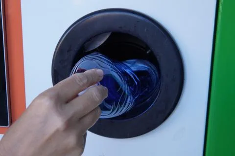 Returning bottles to a plastic recycling machine. 스톡 사진