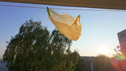 Reusable bag fluttering on clothesline balcony at sunset Stock Footage 331441968