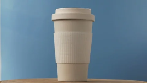 Reusable bamboo coffee cup rotating on the blue background Video stock 115368064