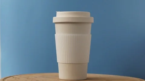 Reusable bamboo coffee cup rotating on the blue background Stock Footage 115368132