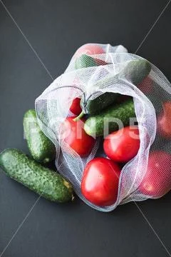 Reusable eco-friendly bag full of fresh seasonal tomatoes and cucumbers Stock Photos