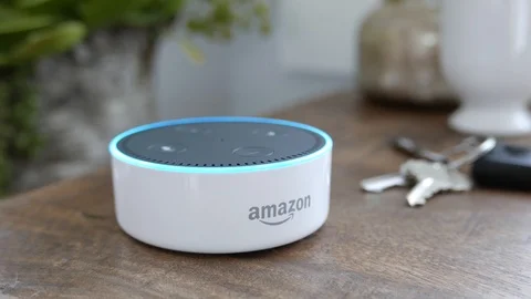 Reveal of Amazon Echo Dot as it sit on a desk and lights up blue.  Editorial. Video stock 103320524