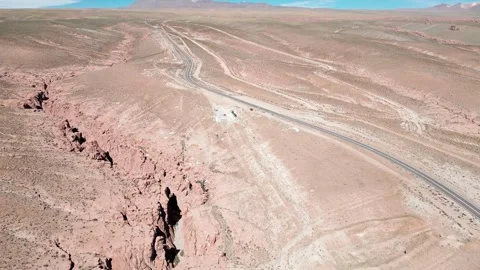 Reveal flight over dramatic rocky canyon edge unveiling straight desert highway Stock Footage 335217066