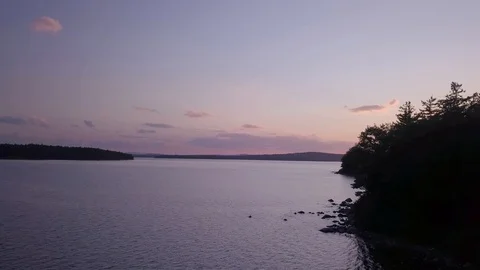 Reveal of Sunset around Corner of Tree Lake Shore Stock Footage 129457119