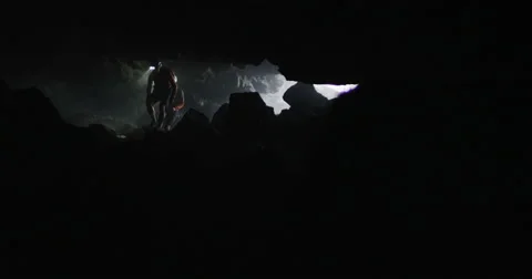 Reveal two explorers entering a cave slider shot slow motion through smoke Stock Footage 64682535