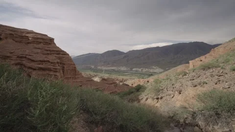 Reveal of a valley below red cliffs, Kyrgyzstan Stock Footage 347242899
