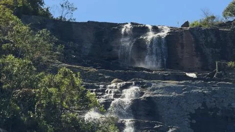 Revealing Multi-Level Waterfall Through Bushes in Slow Motion Foto stock
